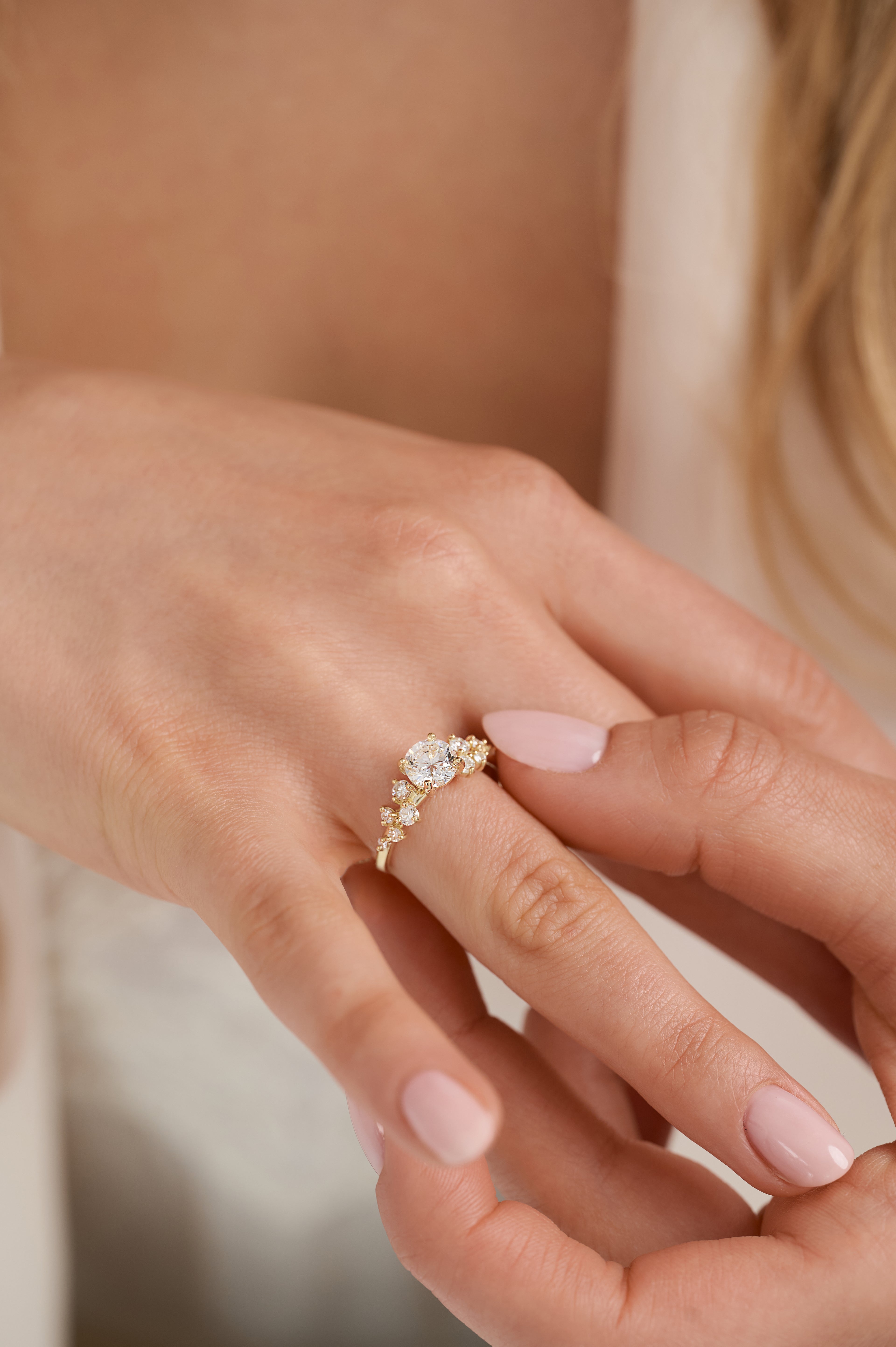 Close-up of a hand wearing a gold ring with a diamond on a blurred background