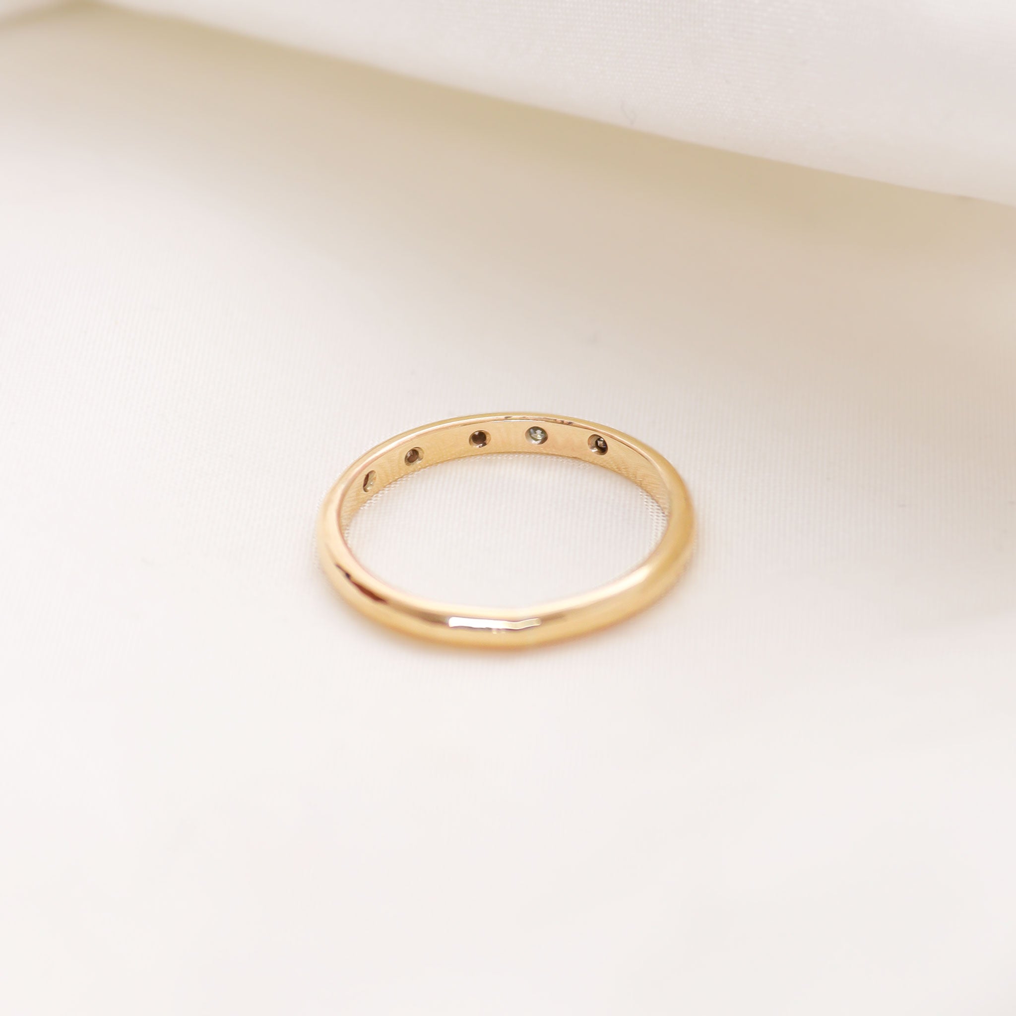 The reverse of Lavey London's Solid Gold Diamond Flush Set Wedding Band presented against a white fabric background