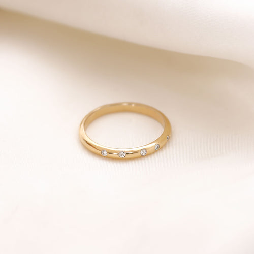 Lavey London's Solid Gold Flush Set Diamond Wedding Band Against A White Fabric Background